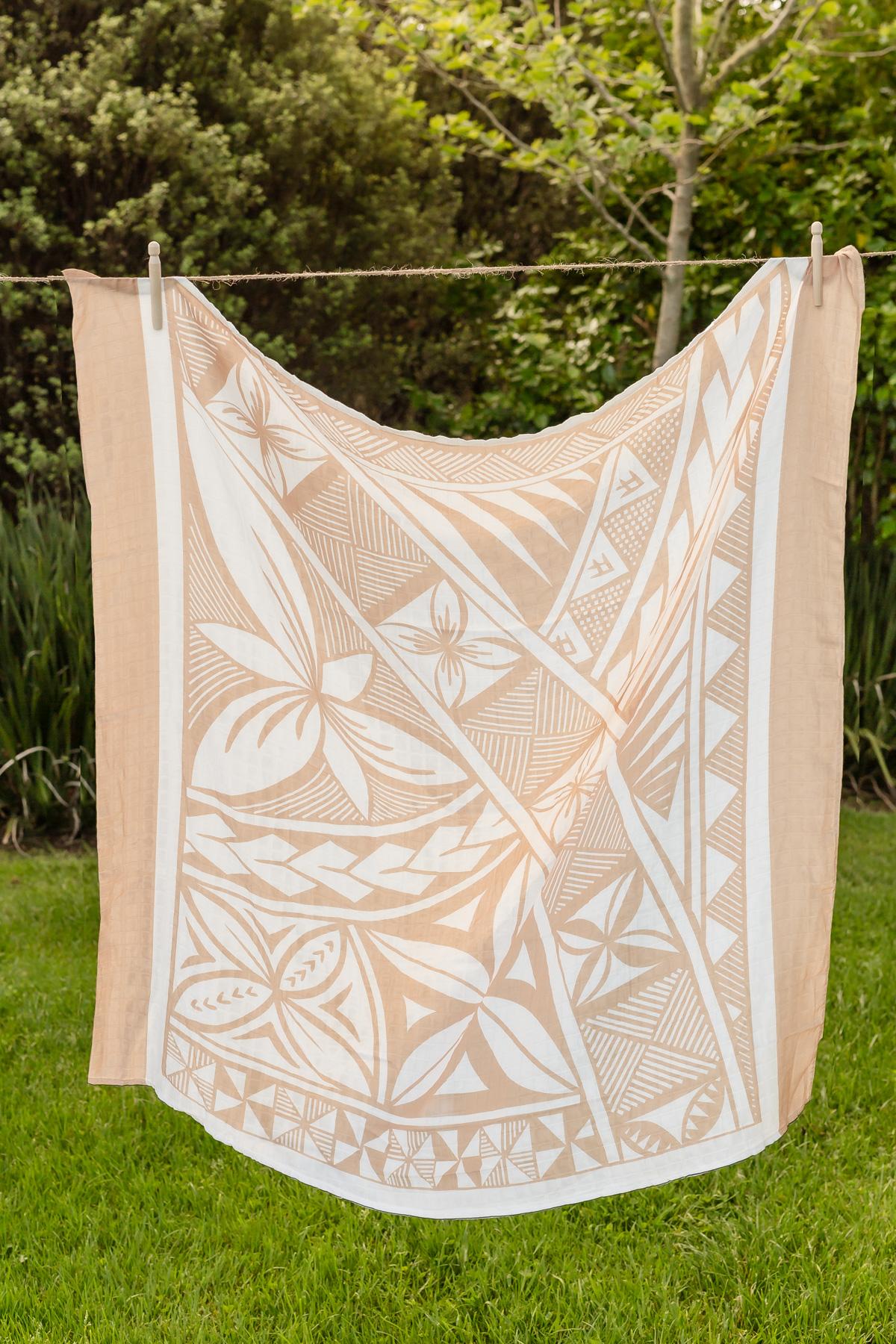 Beige polynesian inspired baby blanket hanging on a clothes line