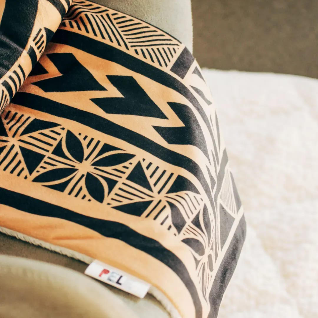 Yellow and black polynesian inspired mink blanket draped over a couch