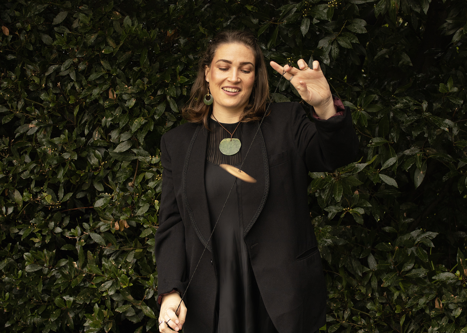 Woman in front of green bush wearing maori pounamu