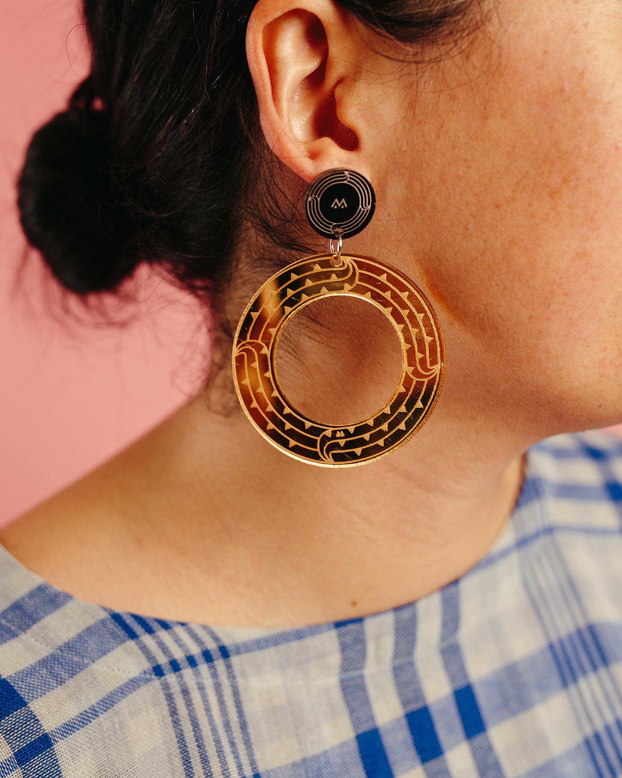 Close up shot of polynesian woman wearing yellow and nblack maori inspired earrings