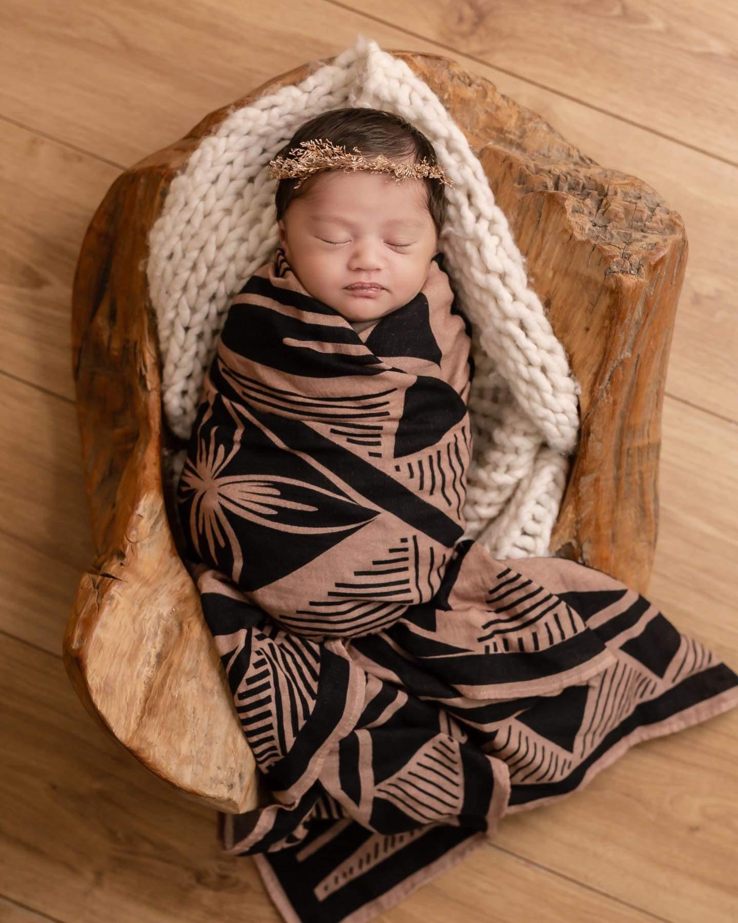 Cozy baby wrapped in polynesian inspired black and brown baby wrap