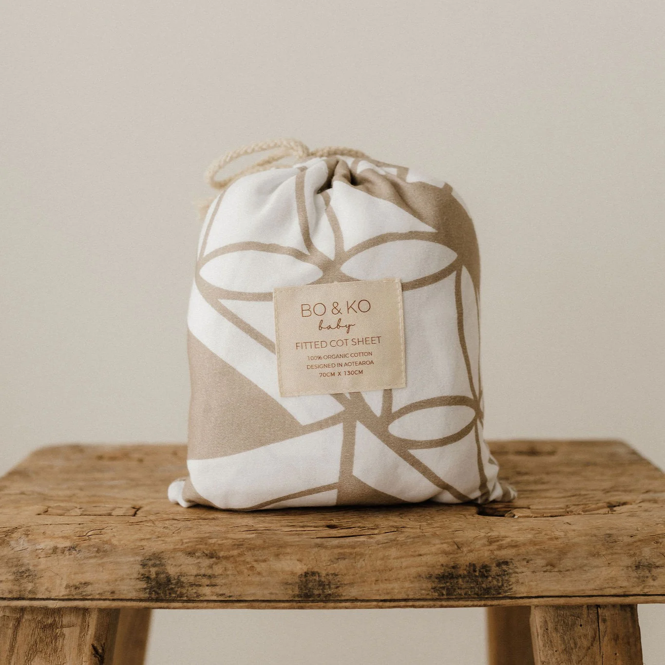 Cloth bag containing polynesian inspired baby cot sheet on a wooden table